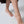 Person wearing a black anklet with a gold charm on a light gray background