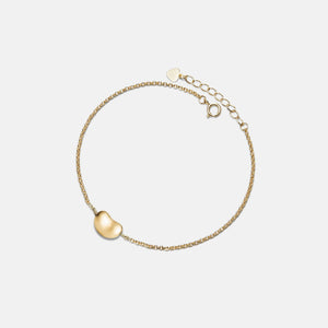 Gold bracelet with a heart-shaped charm on a light gray background