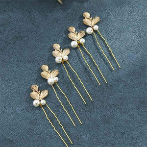 Set of gold hair pins with leaf and pearl details on a dark blue background