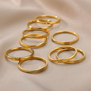 Gold rings with engraved numbers on a beige fabric background