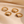 Four gold rings with gemstones on a beige fabric background