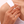 Close-up of a hand wearing a gold ring with a clear gemstone on a white background