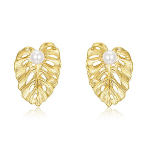 Gold leaf-shaped earrings with pearl centers on a white background