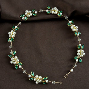 Delicate necklace with pearls and green stones on a brown background