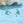 Starfish-shaped earrings with turquoise and silver details on a blue surface with seashells.