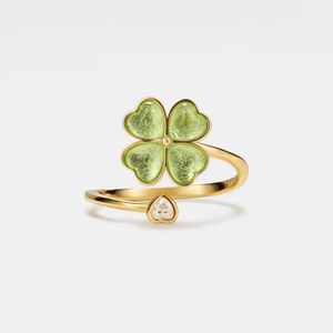 Gold ring with green clover-shaped design on a light beige background