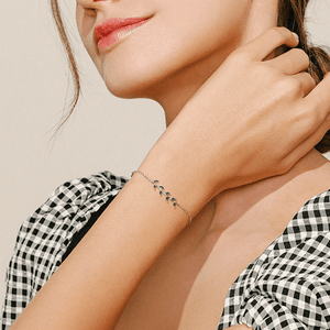 Close-up of a woman wearing a delicate bracelet on a neutral background