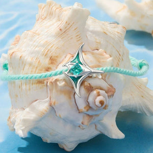 Mint green bracelet with a silver manta ray charm on a blue textured background