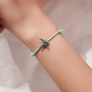 Bracelet with manta ray charm on a wrist against a neutral background