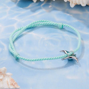 Mint green bracelet with a silver manta ray charm on a blue textured background