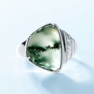 Silver ring with a green stone on a light blue background