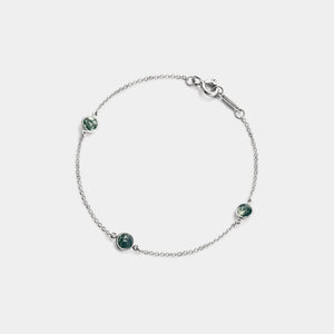 Silver bracelet with green gemstones on a light gray background