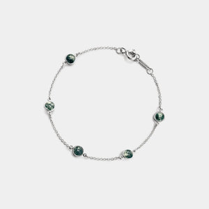 Silver bracelet with green gemstones on a white background