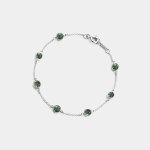 Silver bracelet with green gemstones on a white background