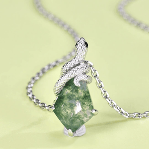 Necklace with a green gemstone and silver snake-shaped pendant on a light green background