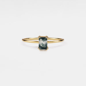 Gold bracelet with a green gemstone on a white background