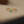 Gold ring with a green gemstone on a beige surface