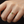 Gold ring with a green gemstone on a finger against a dark background