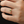 Gold ring with a green gemstone on a person's finger against a dark background