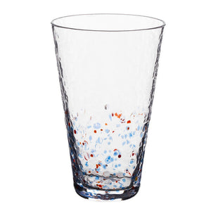 A multicolored dotted glass for drinks with a clear body and red, blue, and orange dots scattered around the interior.