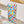 A multicolored hand-painted grid woven drinking glass with a geometric pattern, displayed on a table.