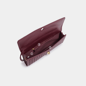 Open maroon handbag with gold hardware on a light gray background