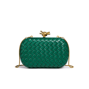 Green woven handbag with gold accents on a white background