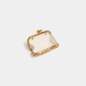 Gold frame clutch with a white interior on a light gray background