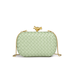 Light green woven handbag with a gold knot detail on a white background