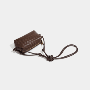 Brown woven leather pouch with a strap on a light gray background