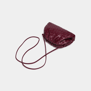Maroon woven handbag with a strap on a light gray background