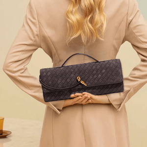 Woman holding a dark woven handbag against a neutral background