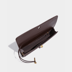 Brown leather clutch bag with gold hardware on a light gray background