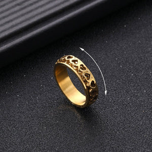 Gold ring with intricate design on a black textured surface