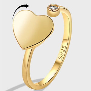 Gold heart-shaped ring with a diamond on a light gray background
