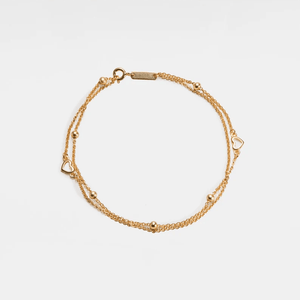 Gold bracelet with heart-shaped links on a light beige background