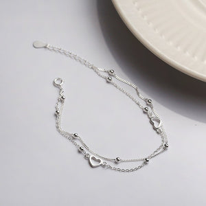 Silver bracelet with heart charms on a light gray surface