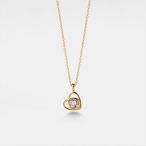 Gold necklace with a heart-shaped pendant on a light gray background