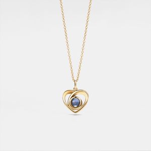 Gold heart-shaped necklace with a blue gemstone on a light gray background