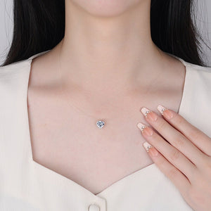 Necklace with a blue gemstone worn by a person, with a hand touching the necklace.