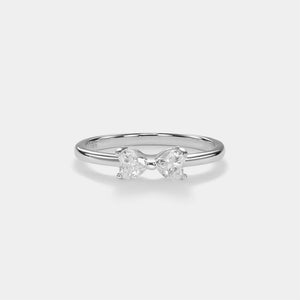 Silver bow-shaped ring with two diamonds on a light gray background