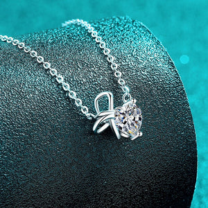 Silver necklace with a heart-shaped pendant on a textured black surface with a teal background