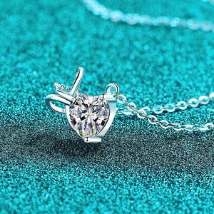 Silver heart-shaped pendant necklace on a textured teal background