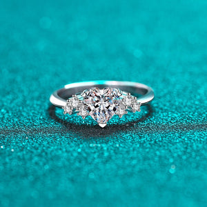 Silver ring with a heart-shaped diamond on a teal background