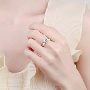 Close-up of a hand wearing a silver ring with a diamond on a light pink background