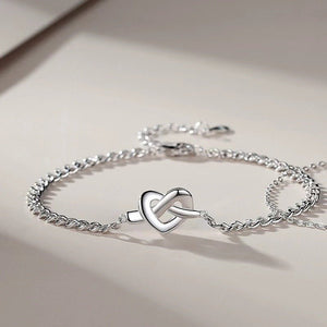 Two silver bracelets with heart-shaped knots, one with a chain link and the other with a solid pattern, placed side by side.