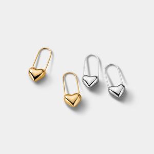Four heart-shaped earrings in gold and silver on a light gray background