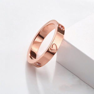 Two rings, one with a gold plating and the other with a silver plating, both featuring a heart-shaped design on the top surface.