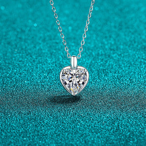 Heart-shaped diamond pendant on a chain against a teal background