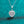 Heart-shaped diamond pendant on a chain against a teal background